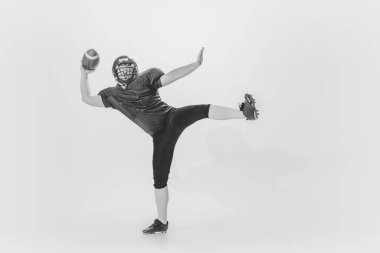 Powerful throw. Studio shot of american football player training with ball isolated on white background. Concept of sport, achievements, retro fashion style. Monochrome
