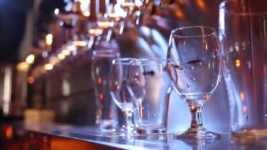 Bartender pouring beer into glasses at pub in neon light. Close-up view of barmans hand filling glass with light beer. Beer craft. Bar table. Oktoberfest, party, drinks, taste and alcohol concept.