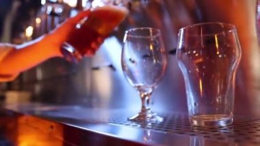 Closeup view of clean beer glasses. Bartender pouring beer into glasses at pub in neon light. Vintage style. Beer craft. Bar table. Oktoberfest, party, drinks, taste and alcohol concept.