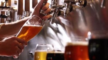 Bartender pouring beer into glasses at pub in neon light. Close-up view of barmans hand filling glass with light beer. Beer craft. Bar table. Oktoberfest, party, drinks, taste and alcohol concept.