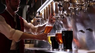 Bartender pouring beer into glasses at pub in neon light. Close-up view of barmans hand filling glass with light beer. Beer craft. Bar table. Oktoberfest, party, drinks, taste and alcohol concept.
