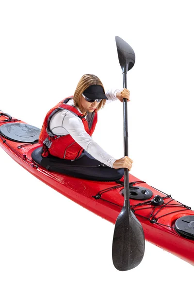 Rowing. Young woman, sportsman in red canoe, kayak with a life vest and a paddle isolated on white background. Concept of sport, nature, travel, active lifestyle