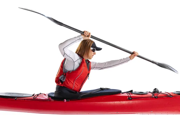 Profile view. Young woman, sportsman in red canoe, kayak with a life vest and a paddle isolated on white background. Concept of sport, nature, travel, active lifestyle