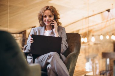 Young girl and her team. Beautiful young confident woman at loft style office with group of colleagues in background. Concept of success, business, career, achievements. looks happy, excited