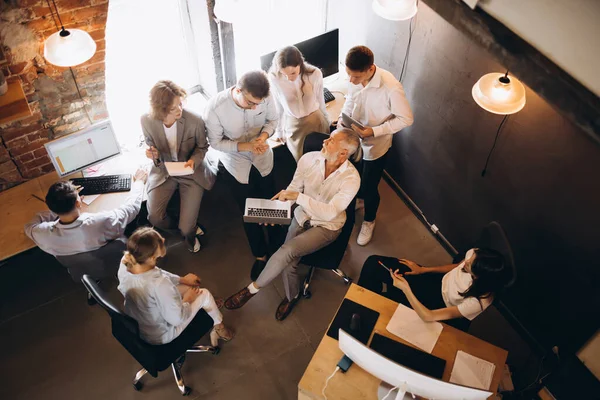 Aerial view. Impressive senior man, professor helds master class, workshop for his students, young employees in loft style office. Successful corporate teamwork. Concept of business, studying, career