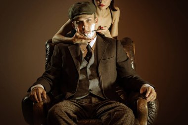 Care. Vintage style portrait of man and woman in 1920s style fashion outfits isolated over dark brown background. Concept of business, personality, emotions, family, art, fashion