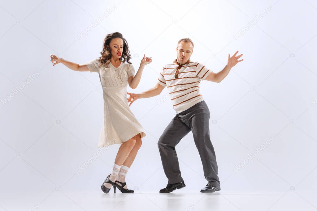 Music and dance. Astonished young man and woman in retro style outfits dancing lindy hop isolated on white background. Timeless traditions, 60s ,70s american fashion style. Emotions, expressions