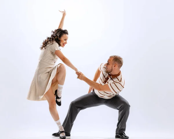 Emotions, expressions and feelings in movements. Dynamic portrait of emotional man and woman dancing sport dances isolated on white background. Timeless traditions, 60s ,70s american fashion style.