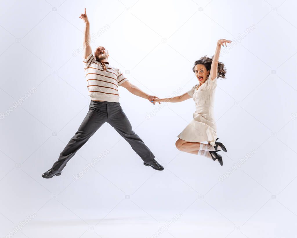 Jumping. Astonished young dancing man and woman dance sport dances isolated on white background. Timeless traditions, 60s ,70s american fashion style.