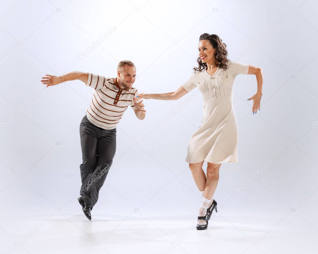 On the same wavelength. Astonished young dancing man and woman dance sport dances isolated on white background. Timeless traditions, 60s ,70s american fashion style.