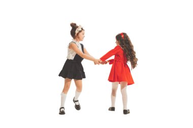 Running away. Studio shot of little happy girls in retro style outfit, fashion of 70s, 80s years isolated on white background. Concept of emotions, facial expression, beauty. Copy space for ad