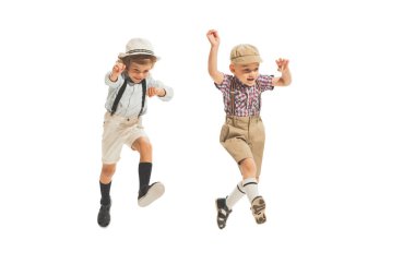 Fun, joy. Two preschool age boys, stylish kids wearing retro clothes running isolated over white background. Concept of childhood, vintage summer fashion style. Copy space for ad