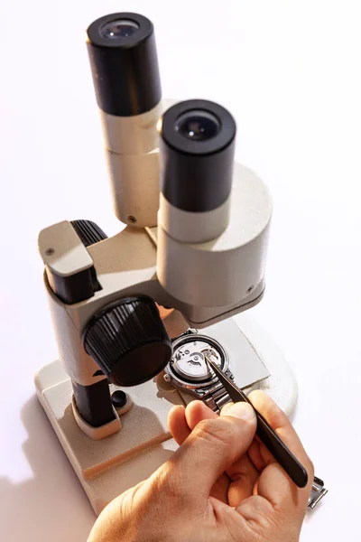 Use of special equipment for watch repair. Closeup watchmakers hands repairing mechanical watches isolated over white background. Concept of vintage retro mechanisms, job, work, ad