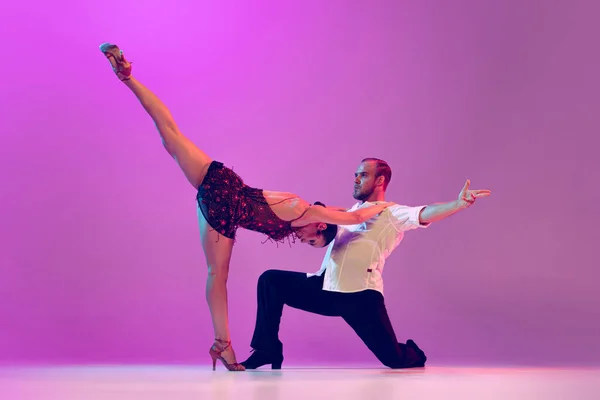 Passion, love, support. Young man and woman, ballroom dancers in motion isolated on purple background. Concept of art, dance, beauty, music, style. Copy space for ad. International Dance Day