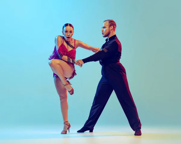 Emotions. Beautiful woman and man, professional dancers dancing ballroom dance isolated on blue background. Concept of art, dance, beauty, music, style. Copy space for ad. International Dance Day