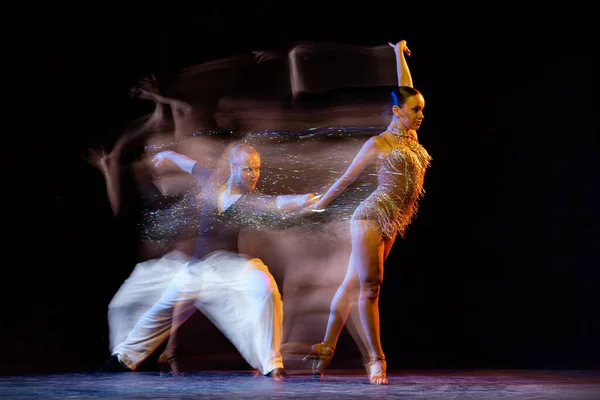 Delight. Two professional dancers dancing ballroom dance isolated on dark background with mixed light. Concept of art, dance, beauty, music, style. International Dance Day