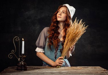 Dreams. Creative portrait of young beautiful redhead girl with long curly hair in image of medieval person in renaissance style dress isolated on dark background. Comparison of eras