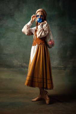 Vintage style. Young charming redhair girl with long curly hair like girl of renaissance eras isolated on dark background. Comparison of eras, beauty, history, art, creativity.