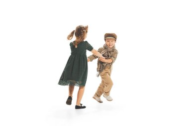 Portrait of children, boy and girl in vintage clothes playing together, having fun, posing isolated over white studio background. Concept of childhood, game, school, fun, education. Copy space for ad