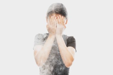 Deep despair. Young dark hair woman close her face with hands isolated over white background with clouds of smoke. Concept of mental health, art, human emotions, challenges, ad
