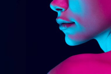 Fantasy. Closeup female lips, cheeks and nose isolated over dark background in neon light. Natural beauty. Concept of natural beauty, cosmetology, skincare, cosmetics, plastic surgery, ad