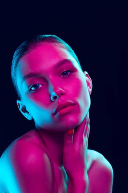 Perfection. Portrait of tender young woman with well-kept skin posing isolated over dark background in neon light. Concept of natural beauty, art, emotions, cosmetics and youth