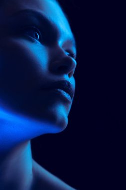 Marvelous night. Closeup portrait of young woman in neon light on dark background. Monochrome. Cyberpunk style, beauty, cosmetics concept. Serious and thoughtful