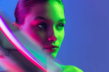 Femininity and softness. Portrait of young, beautiful and healthy girl with well-kept skin isolated on dark background in neon light. Art, fashion, style, facial expression, eco products and health