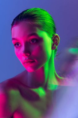 Serious and thoughtful. Attractive young, beautiful girl with well-kept skin isolated on blue background in neon light. Art, fashion, style, facial expression, eco products and health