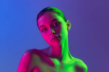 Femininity and softness. Portrait of young, beautiful and healthy girl with well-kept skin isolated on dark background in neon light. Art, fashion, style, facial expression, eco products and health