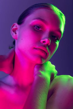 Night life. Young adorable sad girl posing isolated over blue background in neon light. Concept of natural beauty, art, emotions, cosmetics and youth. Flyer for ad. Looks calm