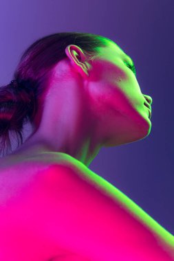 Close up female neck and shoulders in pink neon light over dark background. Beautiful young womans body with well-kept skin. Beauty, fitness, diet, spa, plastic surgery and aesthetic cosmetology