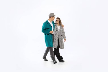 Evening strolling. Young married couple, young man and woman in 70s, 80s fashion style attires isolated on white background. Relationships, love, care. Concept of culture, art, music, style, ad