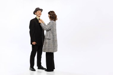 Fall wardrobe fitting. Happy couple, young man and woman in 70s, 80s fashion style attires isolated on white background. Relationships, love, care. Concept of culture, art, music, style, ad