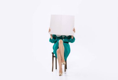 Breaking news. Portrait of woman in retro, 70s, 80s fashion style clothes, vintage outfit reading newspaper isolated on white background.
