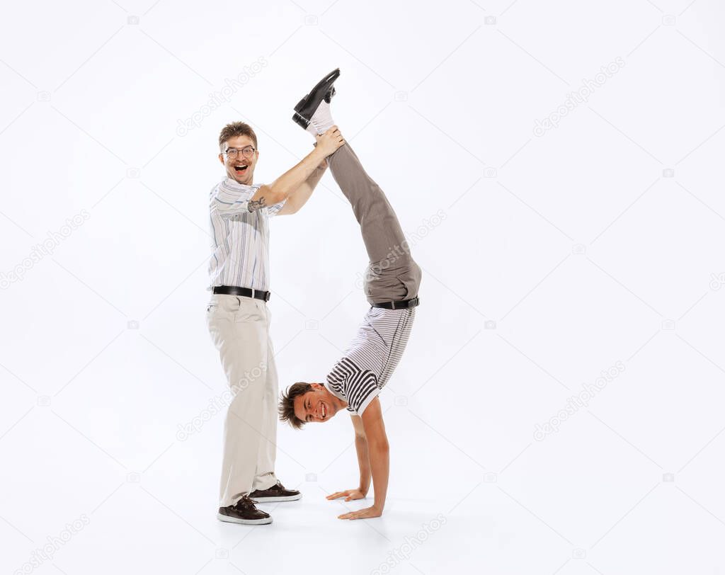 Support, help, assist. Two cheerfull dudes, young men having fun isolated on white background. Artists in motion. Concept of culture, art, music, style, ad