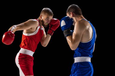 Training. Young men, professional boxers in red and blue sports uniform boxing isolated on dark background. Concept of sport, skills, power, training, energy. Copy space for ad, text