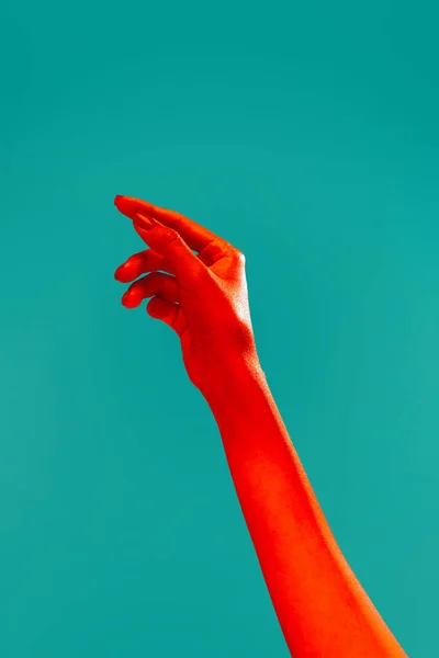 Supplication. Female hand reaching up isolated on cyan color background in red neon light. Concept of relationship, community, care, support, symbolism, culture. Copy space for ad