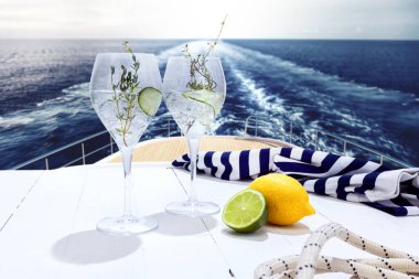 Yacht trip. Glasses with fresh lemonade, cocktail with cucumber on deck of luxury cruise ship during honeymoon holidays, outdoors. Love, travel, vivid impressions. Design for wallpaper, poster