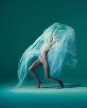 Emotions in dance. Graceful ballet dancer dancing with white cloth, fabric isolated on green background. Concept of art, motion, action, flexibility and inspiration concept. Blurring effect