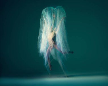 Flight. Creative portrait of flexible ballet dancer in motion with white cloth, fabric isolated on green blue background. Art, beauty, creation, inspiration concept. Blurring effect