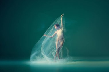 Tenderness. Beautiful and graceful ballet dancer dancing with white transparent cloth, isolated on cyan color background. Concept of art, flexibility and inspiration concept. Blurring effect