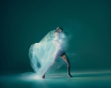 Emotions in dance. Graceful ballet dancer dancing with white cloth, fabric isolated on green background. Concept of art, motion, action, flexibility and inspiration concept. Blurring effect