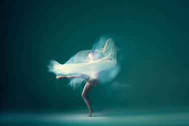 Emotions in dance. Graceful ballet dancer dancing with white cloth, fabric isolated on green background. Concept of art, motion, action, flexibility and inspiration concept. Blurring effect
