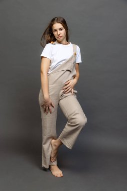 Young charming girl with long hair in casual style clothes posing isolated over dark grey background. Wellness, wellbeing, bodypositive, fashion concept. Model looks happy, calm