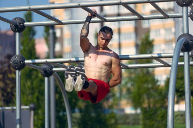 Workout. Strong muscular man, student training, practicing at sport ground at public park in summer morning, outdoors. Action, skills, challenges and achievements concept