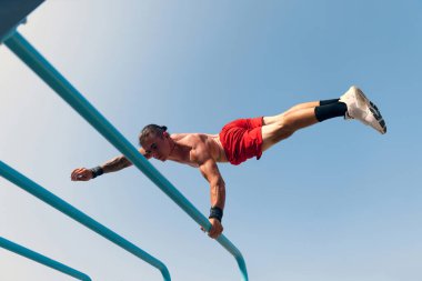 Workout. Strong muscular man, student training, practicing at sport ground at public park in summer morning, outdoors. Action, skills, challenges and achievements concept