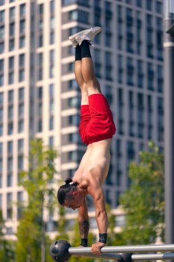 Workout. Strong muscular man, student training, practicing at sport ground at public park in summer morning, outdoors. Action, skills, challenges and achievements concept
