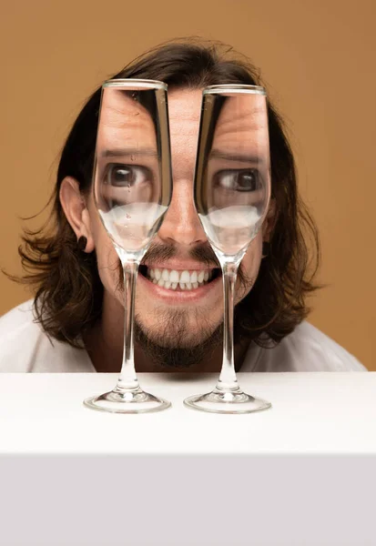 Happiness. Weird emotions, facial expression concept. Happy mans face through wine glasses. Object distortion, optical illusion. Minimalistic contemporary art. Poster