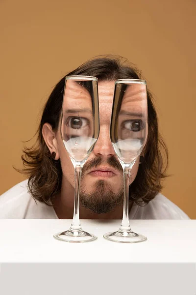 Surprise. Weird emotions, facial expression concept. Happy mans face through wine glasses. Object distortion, optical illusion. Minimalistic contemporary art. Poster